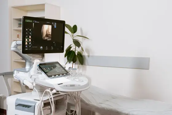 An ultrasound and scanning unit beside an examination couch in a clinic room