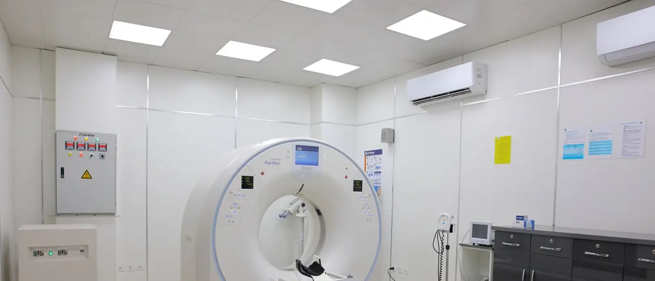A bright, sterile hospital imaging room built around a large ring-shaped scanner