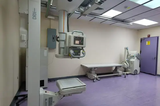 A radiography room with a ceiling-mounted X-ray tube above a patient table