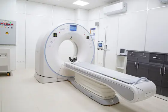 A magnetic resonance scanner and its patient table in a bright, empty imaging room