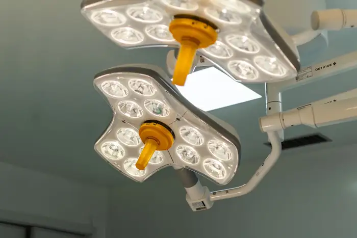 Two large multi-lamp surgical lights above an operating table