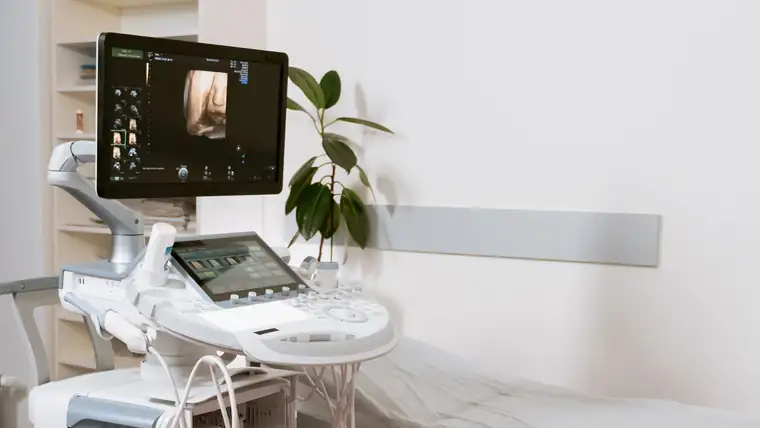 An ultrasound and scanning unit beside an examination couch in a clinic room