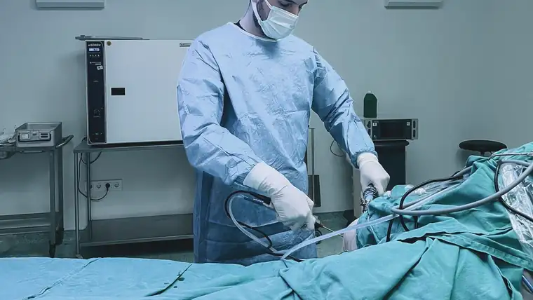 A gowned clinician working at an endoscopy stack in a procedure room